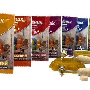 May include: Assortment of six small packets of food coloring for dyeing Easter eggs. The packets are labeled with the colors: Yellow, Orange, Red, Violet, Blue, and Green. The packets are arranged in a row from left to right. Each packet contains 3 grams of food coloring. The packets are on a white background.