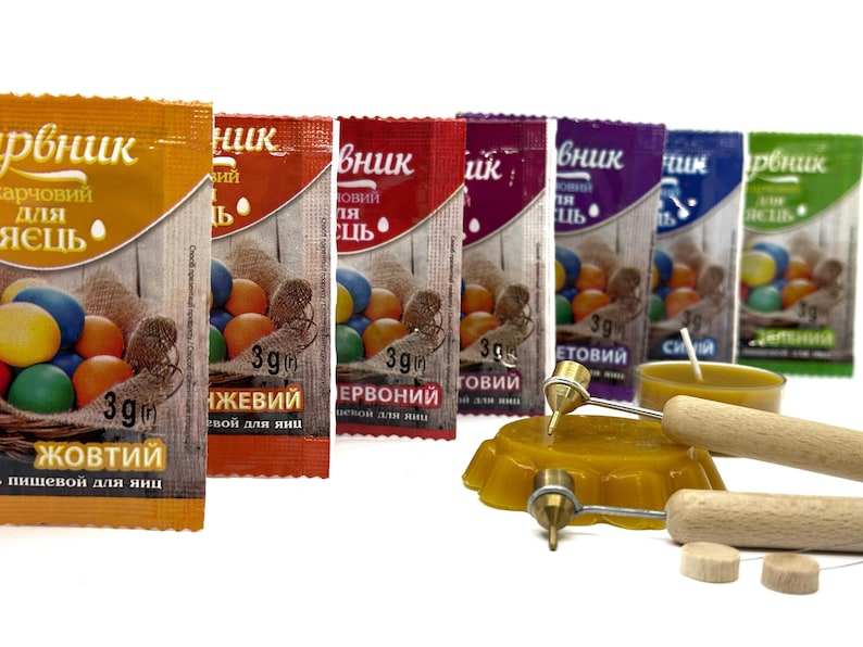 May include: Assortment of six small packets of food coloring for dyeing Easter eggs. The packets are labeled with the colors: Yellow, Orange, Red, Violet, Blue, and Green. The packets are arranged in a row from left to right. Each packet contains 3 grams of food coloring. The packets are on a white background.