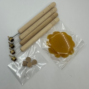 May include: Set of five wooden tools with brass tips and a small bag of wooden tips. A clear plastic bag contains a round disc of yellow wax.