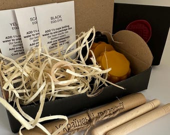 Peut inclure: Un kit de loisirs créatifs dans une boîte noire contenant trois fiches d'instructions blanches pour colorant à œufs, des disques de cire jaune et noire, un anneau en bois et des copeaux. Deux outils kistka en bois avec pointes en laiton.