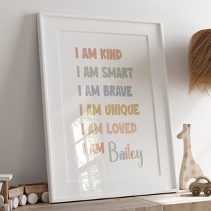 K&ouml;nnte beinhalten: Ein wei&szlig;er gerahmter Druck mit dem Text "I AM KIND", "I AM SMART", "I AM BRAVE", "I AM UNIQUE", "I AM LOVED" und "I AM Bailey" in bunten Farben.