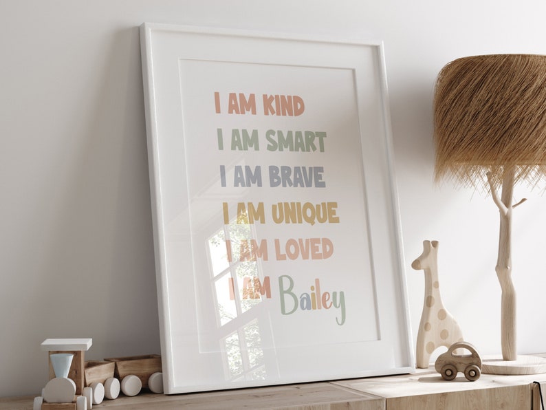 K&ouml;nnte beinhalten: Ein wei&szlig;er gerahmter Druck mit dem Text "I AM KIND", "I AM SMART", "I AM BRAVE", "I AM UNIQUE", "I AM LOVED" und "I AM Bailey" in bunten Farben.