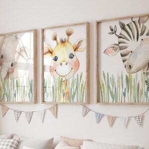 May include: Three framed watercolor paintings of animals peeking out from behind tall green grass. The animals are a giraffe, a zebra, and an elephant. The paintings are in wooden frames.