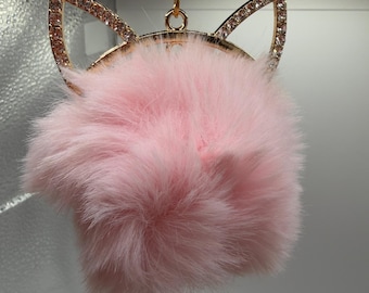 Può includere: Un portachiavi rosa e soffice con un design a orecchie di gatto color oro. Le orecchie di gatto sono impreziosite da piccoli strass trasparenti. Il portachiavi ha una catena color oro.