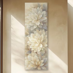 May include: Vertical canvas art featuring three large, cream-colored dahlia flowers. The floral painting has soft, neutral tones of cream, beige, and gray, creating a calming and elegant aesthetic. The artwork is displayed on a light-colored wall.