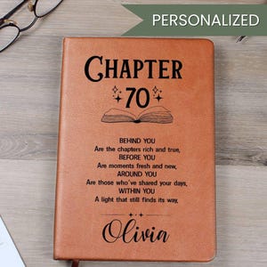 May include: A personalised brown leather journal with the text "CHAPTER 70" and the name "Olivia". The journal features an open book graphic and a poem about life's chapters.