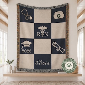 May include: A beige and navy blue woven throw blanket with a checkerboard pattern. The design includes medical symbols, a graduation cap with "2026", the name "Olivia", and the text "RN". The blanket is made of 100% cotton.