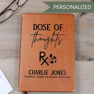 Puede incluir: Un diario de cuero marrón con las palabras "DOSE OF thoughts" y el símbolo "Rx". El diario está personalizado con el nombre "CHARLIE JONES" y el texto "A PHARMACY JOURNAL FOR EVERYDAY REFLECTIONS".