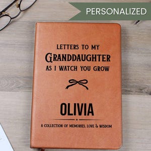 Può includere: Un diario in pelle marrone personalizzato con il testo "Letters to my Granddaughter as I watch you grow" e il nome "Olivia". Il diario include anche il testo "A collection of memories, love & wisdom".