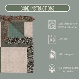 May include: A folded woven blanket with a geometric pattern in beige, green, and gray, with fringed edges. The image includes care instructions: cold wash (max 90&deg;F), low heat, mild detergent, and non-chlorine bleach as needed.