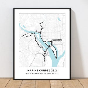 May include: A black and white map with a blue river running through it. The map shows a running route with the text "MARINE CORPS | 26.2" and "NOELLE MOORE | 4:19:02 | OCTOBER XX, XXXX".