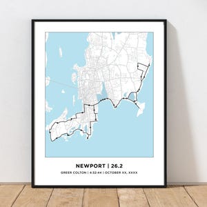 May include: A black and white map of Newport, Rhode Island, with a blue background. The map shows the route of a 26.2 mile race. The text "NEWPORT | 26.2" is at the bottom of the map, along with the text "Greer Colton | 4:32:44 | October XX, XXXX".