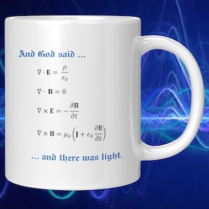 May include: White ceramic coffee mug with a blue inscription that reads "And God said..." followed by four physics equations and the phrase "...and there was light."