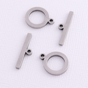 May include: Four silver metal jewelry findings, two are round rings with a small loop on one side, and two are straight bars with a small loop on one end.