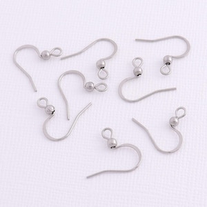 May include: A set of seven silver earring hooks with a small ball at the top of each hook.