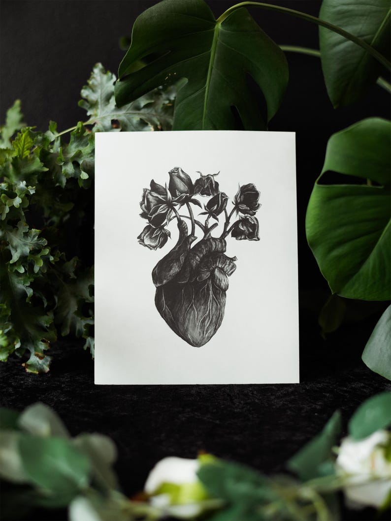 A black and white print of a hand-drawn anatomical heart blooming with wilted roses as though it were a vase. Surrounded by dark green leaves and shadows. Ideal for gothic or anatomy-themed decor.