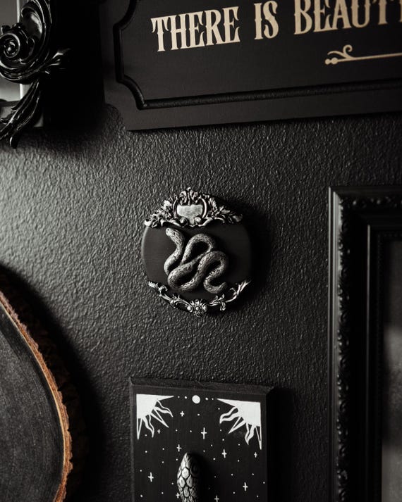 A handmade ornate snake wall hanging with 555 favorites proving demand — fills that awkward gallery wall gap with genuine dark-cottagecore character.