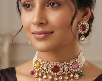 May include: A multi-strand pearl choker necklace featuring a central row of oval-cut yellow, red, and pink gemstones surrounded by clear crystals, with dangling teardrop-shaped pendants and matching circular stud earrings with red centers.