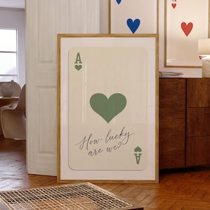 May include: A framed print of an ace of hearts playing card with a green heart and the text "How lucky are we?"