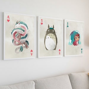 May include: Three framed prints of illustrations featuring characters from the animated film 'My Neighbor Totoro'. The first print features a pink and white dragon, the second print features a grey Totoro, and the third print features a girl with a blue and white hat.