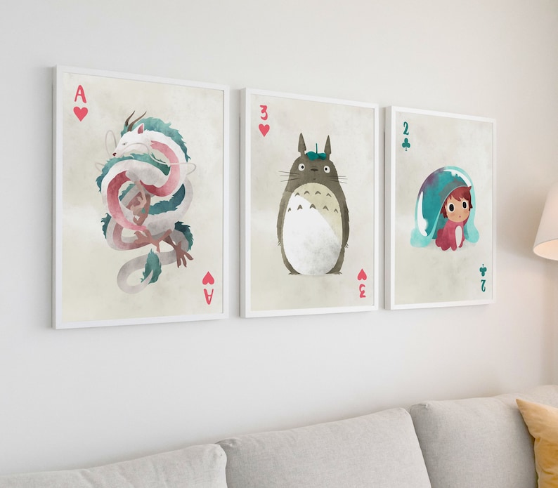 May include: Three framed prints of illustrations featuring characters from the animated film 'My Neighbor Totoro'. The first print features a pink and white dragon, the second print features a grey Totoro, and the third print features a girl with a blue and white hat.