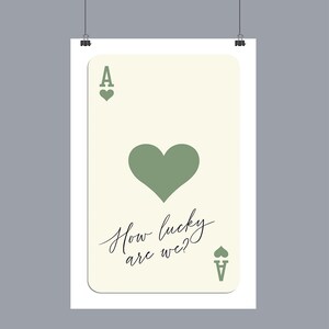 May include: A white card with a green heart and the text "How lucky are we?"  The card is a playing card with the Ace of Spades symbol in the top left and bottom right corners.