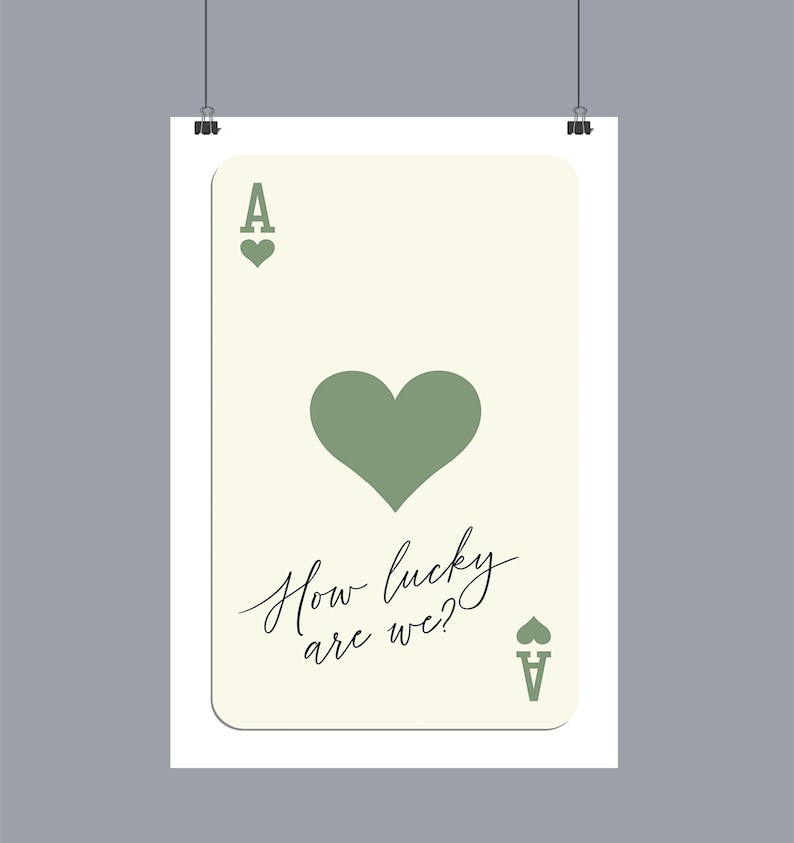 May include: A white card with a green heart and the text "How lucky are we?"  The card is a playing card with the Ace of Spades symbol in the top left and bottom right corners.
