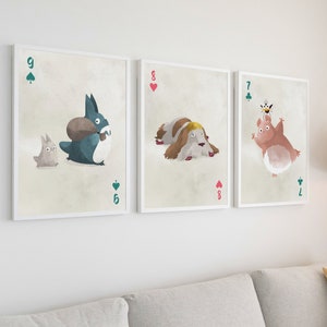 May include: Three framed illustrations of playing cards with cartoon characters. The first card is a 9 of spades with a blue creature carrying a brown object and a small gray creature. The second card is an 8 of hearts with a white dog with brown spots. The third card is a 7 of clubs with a pink creature with a bee on its head.