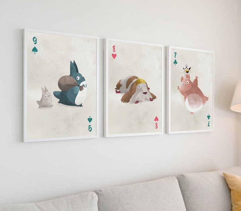 May include: Three framed illustrations of playing cards with cartoon characters. The first card is a 9 of spades with a blue creature carrying a brown object and a small gray creature. The second card is an 8 of hearts with a white dog with brown spots. The third card is a 7 of clubs with a pink creature with a bee on its head.
