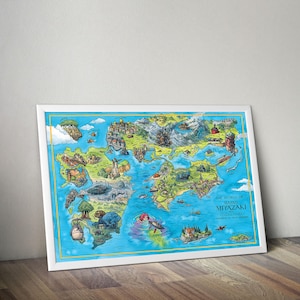 May include: A framed art print showing a detailed, illustrated map of a fantasy world. The map includes various locations and characters, with the text "THE WORLD OF HAYAO MIYAZAKI STUDIO GHIBLI". The frame is white, and the artwork is displayed on a wooden surface.