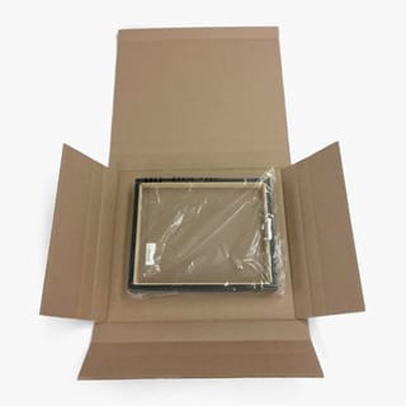 May include: A black picture frame with a clear plastic wrap around it. The frame is inside a brown cardboard box.