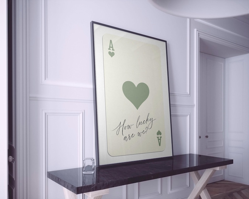 May include: A framed print of an ace of hearts playing card with a green heart and the text "How lucky are we?"