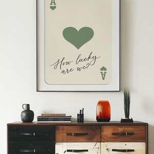 May include: A framed print of an ace of spades playing card with a green heart and the text "How lucky are we?"