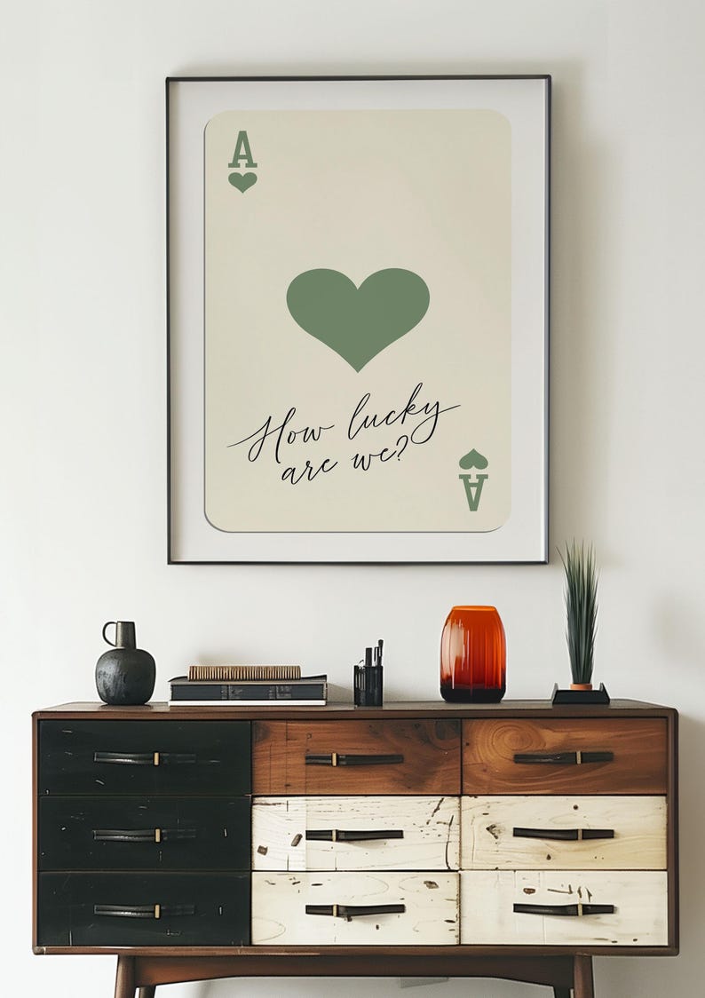 May include: A framed print of an ace of spades playing card with a green heart and the text "How lucky are we?"