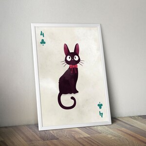 May include: A framed art print featuring a black cat with a red bow tie, resembling a playing card. The artwork includes the number 4 and a green clover symbol. The cat has large, round eyes and long whiskers. The frame is white.