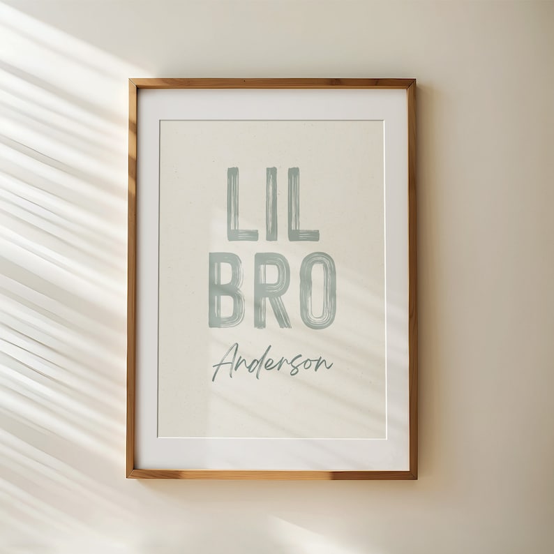 Peut inclure: Une impression encadr&eacute;e avec un fond beige clair et le texte "Lil Bro Anderson" en bleu clair. Le texte est en police d'&eacute;criture de style brosse.