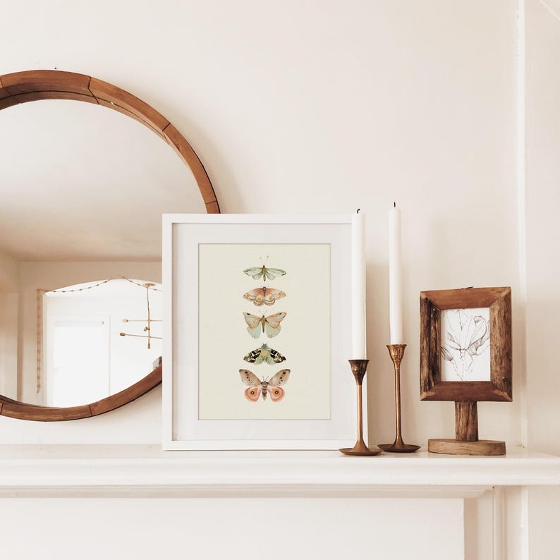 May include: A white framed print with a vertical arrangement of five butterflies in shades of green, pink, and brown on a light green background.