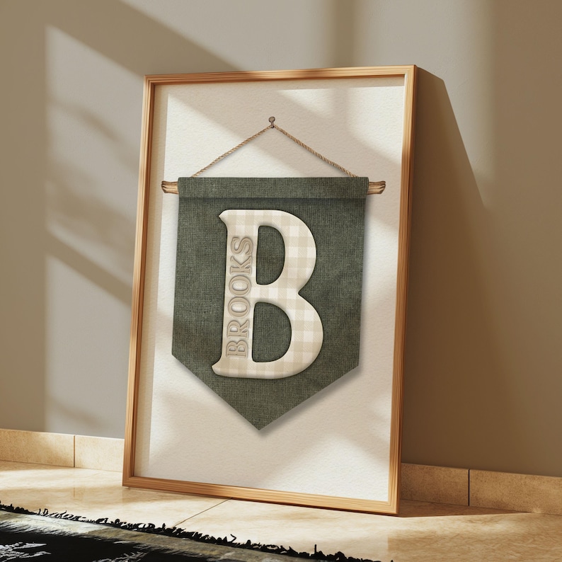 May include: A framed wall banner featuring a large letter "B" with the name "Brooks" vertically printed on the left side. The letter is a cream color with a checkered pattern, set against a dark green banner.
