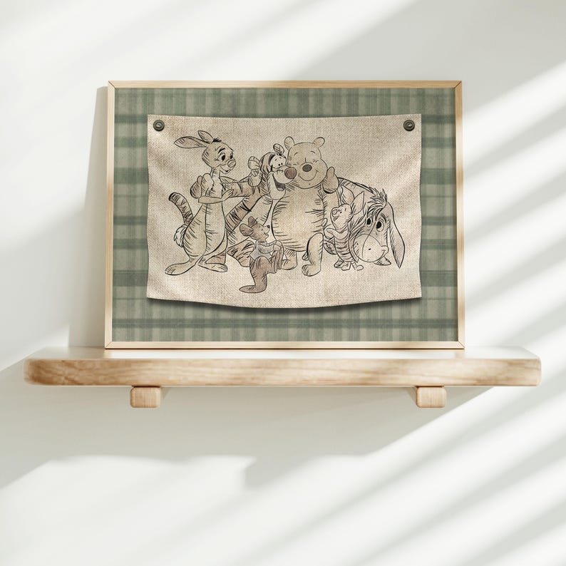 May include: Framed wall art showing a sketch of Winnie the Pooh and friends. The artwork is on a beige fabric with a wooden frame and a green plaid background. The characters include Winnie the Pooh, Tigger, Piglet, Eeyore, and Rabbit.