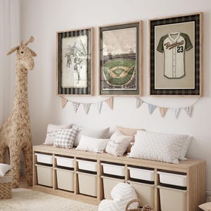 May include: Three framed baseball-themed prints hang above a storage bench. The prints depict a baseball player, a stadium, and a jersey. A woven giraffe and pillows decorate the room. The storage bench has white bins.