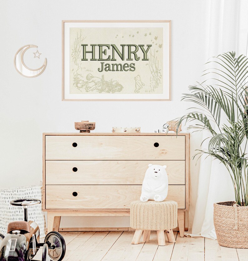 May include: A framed print with the name "HENRY James" in green lettering, displayed above a wooden chest of drawers. The room is decorated with a moon-shaped mirror, a white polar bear plush, and a potted plant. A toy car is visible on the left.