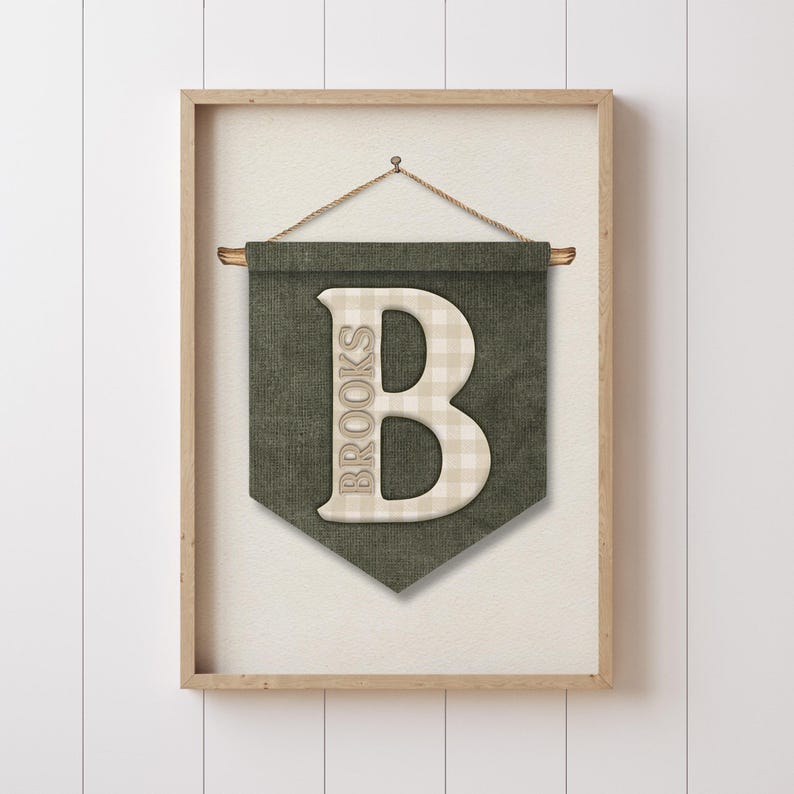 May include: A framed wall banner with a green background and a large, off-white letter "B" in the center. The letter has a plaid pattern. The word "BROOKS" is printed vertically on the left side of the letter. The banner is suspended by a wooden dowel and a rope.