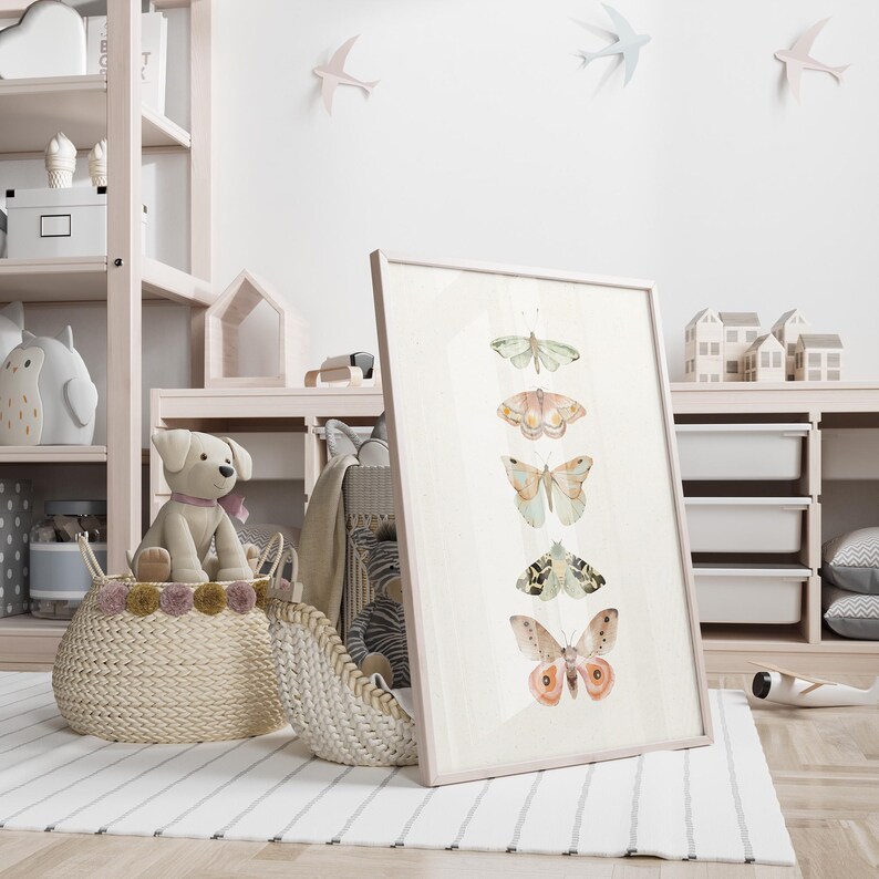 May include: A white framed print with a watercolor illustration of six butterflies in shades of pink, green, and brown. The butterflies are arranged vertically in a row, with the largest butterfly at the bottom.