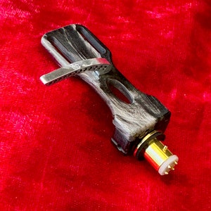 Puede incluir: Un brazo de tono de fibra de carbono negro y blanco con un conector chapado en oro. El brazo de tono está diseñado para usarse con un tocadiscos.