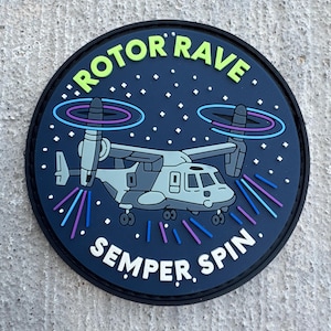 May include: Round patch with a navy blue background featuring a stylized illustration of a military aircraft. The text "ROTOR RAVE" in green arcs across the top, and "SEMPER SPIN" is at the bottom. The aircraft is gray and white.