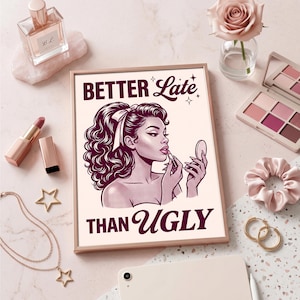 May include: A framed print with the text "BETTER Late THAN UGLY" features a retro illustration of a woman applying lipstick. The image is surrounded by makeup items, jewelry, and a rose in a vase, all in shades of pink and gold.