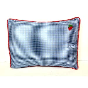 Puede incluir: Cojín rectangular con estampado de cuadros vichy azul y blanco. Tiene un borde rojo y una pequeña fresa bordada. Un elemento decorativo para dormitorio o salón.
