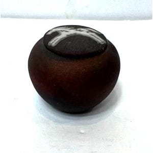 May include: A dark brown, spherical decorative jar with a lid. The lid is a darker shade of brown and features a white, abstract design. The jar has a smooth, polished surface and sits on a white background.