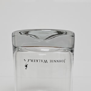 Peut inclure: Verre &agrave; boire transparent avec un dessus l&eacute;g&egrave;rement incurv&eacute;. Les mots "JOHNNIE WALKER" sont imprim&eacute;s en noir, accompagn&eacute;s d'un petit logo. Le verre est clair et est con&ccedil;u pour servir des boissons.