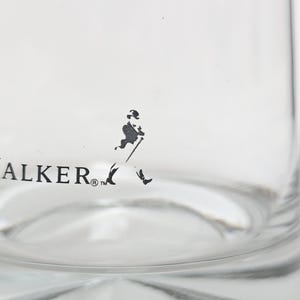 Peut inclure: Verre transparent avec l'inscription "IE WALKER" et une silhouette noire d'un homme marchant avec une canne. Le verre a une base arrondie et une surface lisse et transparente.